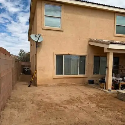 Bare dirt side yard against a block wall