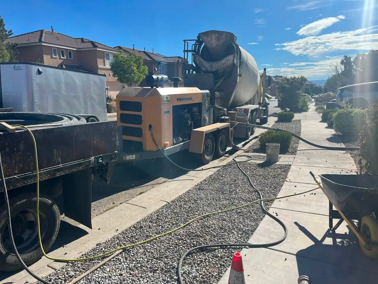Concrete pump trailer and mixer truck at the curb, pumping concrete to the backyard