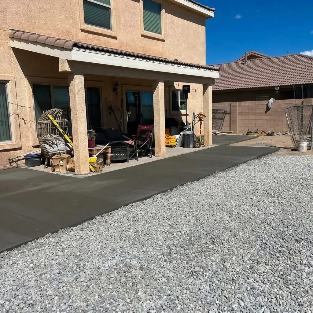 After: the same backyard with a new concrete pad along the patio and gravel across the yard